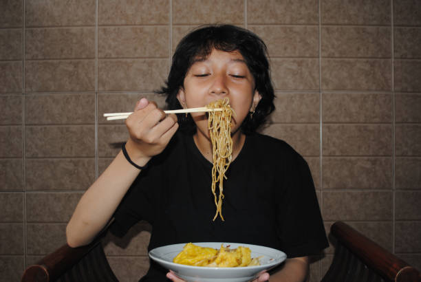 istock Girl eating noodles. 2029641423