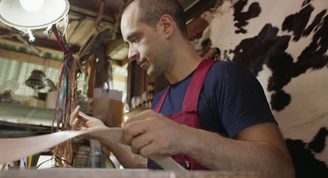 Craftsman in apron doing leather work in craft studio workshop. SME business.