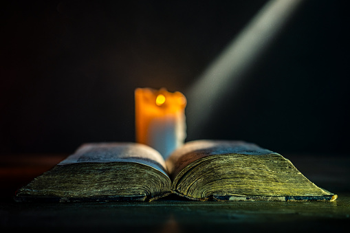 Holy Bible on wooden background in dark room