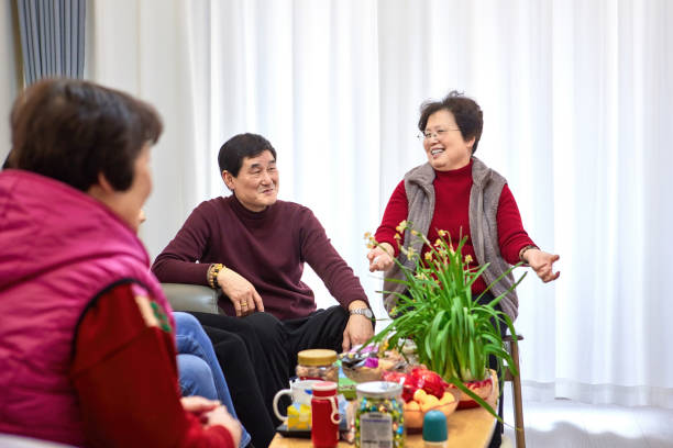 three  senior asian people gathering at home having a good time.