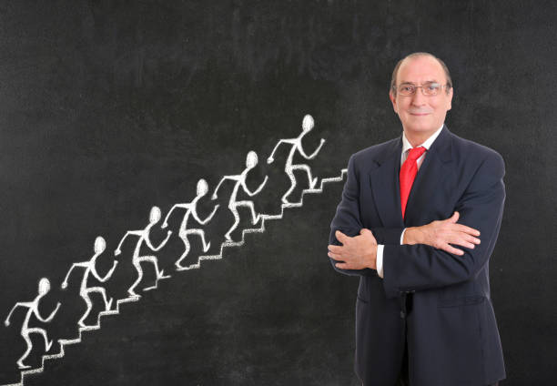 Businessman with stick figure climbing on blackboard