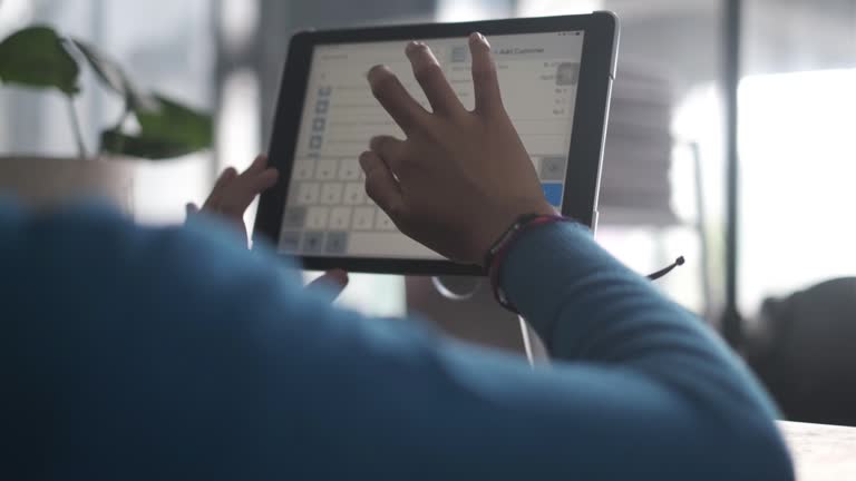 Receptionist Inputting Customer Reservation Data on Digital Tablet