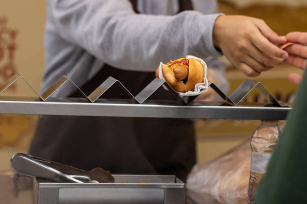 Unrecognizable cook selling hot dog to customer