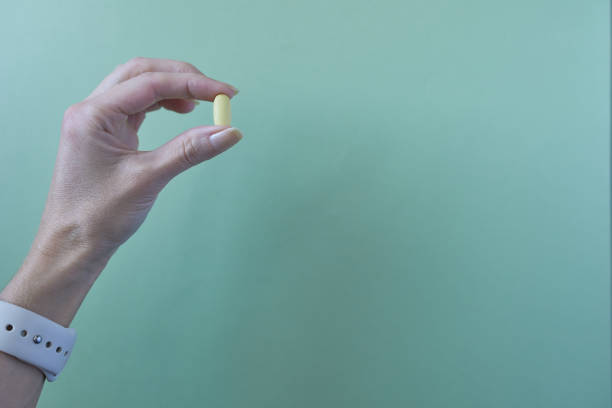 istock A woman's hand holding a pill on a green background 2029715986