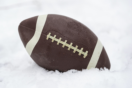 a football covered with snow and laying in the snow. High quality photo