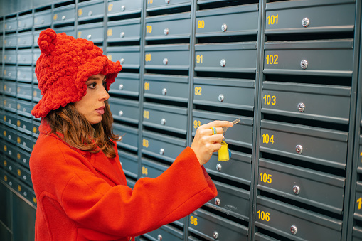 Woman in a fancy hat intends to open a mailbox with a key