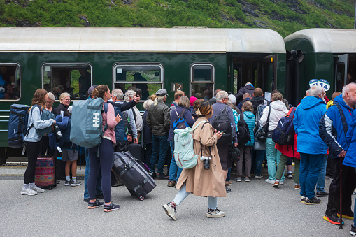 Flam, Norway, June 24, 2023: Travelers board the famous Flamsbana railway, a steep train rid between Flam and Myrdal, which reveals scenes of towering mountains and thick forests.