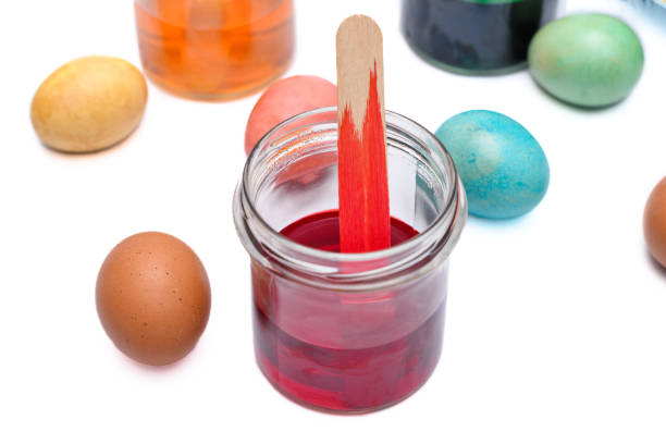 Colorful Easter eggs on a white background and jars with dyes