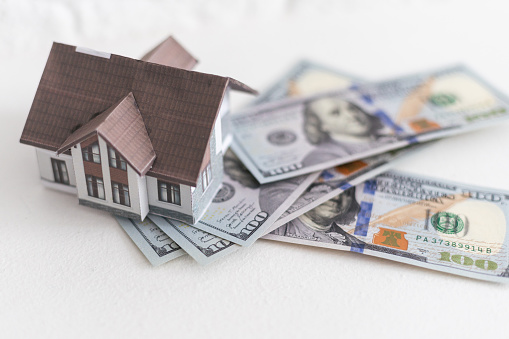 House standing on a pile of dollar bills. Investment, real estate and property concept. High quality photo