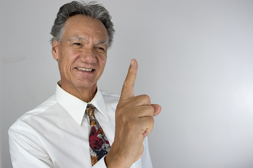 An elderly man happily gesturing number one with finger