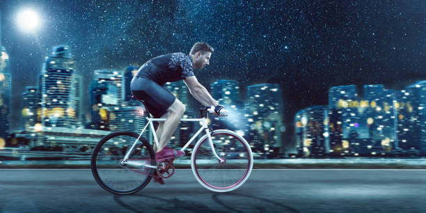 istock Man Riding a Bicycle in Front of a City Skyline at Night 2029853527