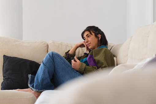 side view portrait of a young confident Hispanic woman relaxed doing leisure activities during happy daily life indoors in her Barcelona apartment.