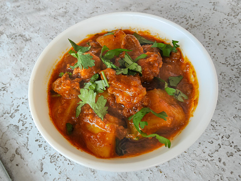 Beef meat and vegetables stew in black bowl. Slate background. Top view.