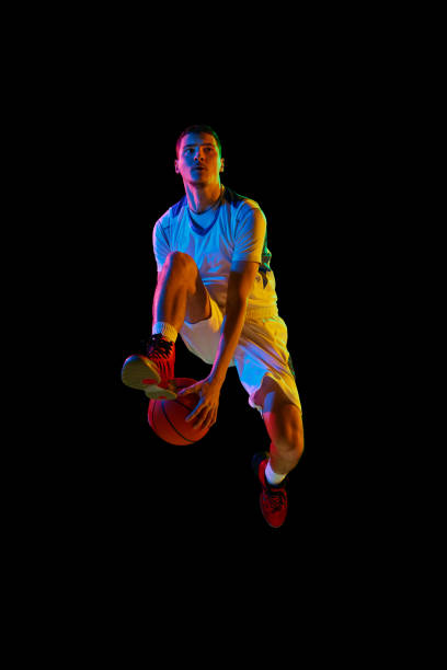 istock Young basketball athlete training dribbling technique in motion against black studio background in mixed neon light. 2029872989