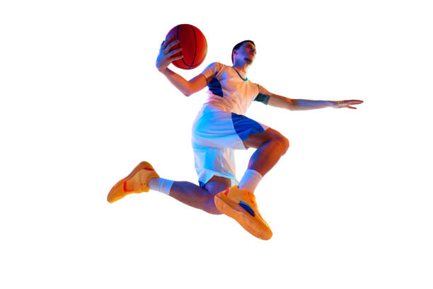 istock Athletic man doing basketball dunk in motion against white studio background in vivid mixed neon light, filter. Match. 2029873539