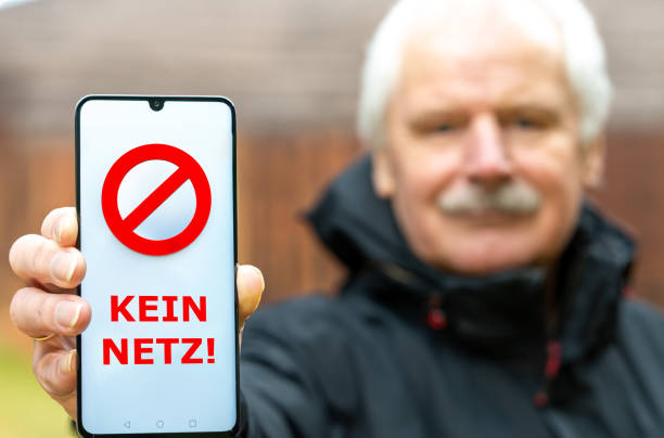 istock Symbol for a bad mobile net coverage. Man shows mobile phone with the German text 'kein Netz' (no signal). 2029892889