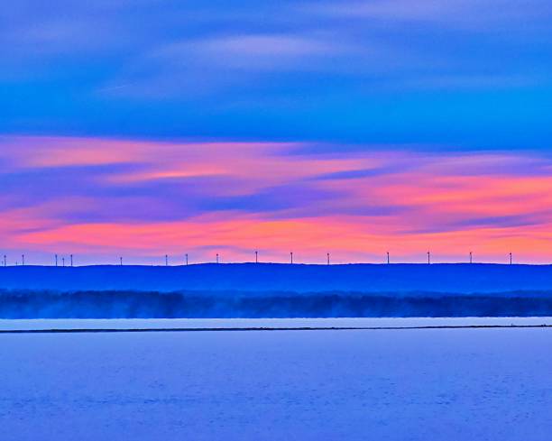 A row  of wind turbine in the horizon on top of a mountain