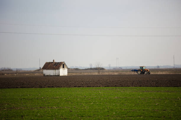 Tractor and abandoned house on a field