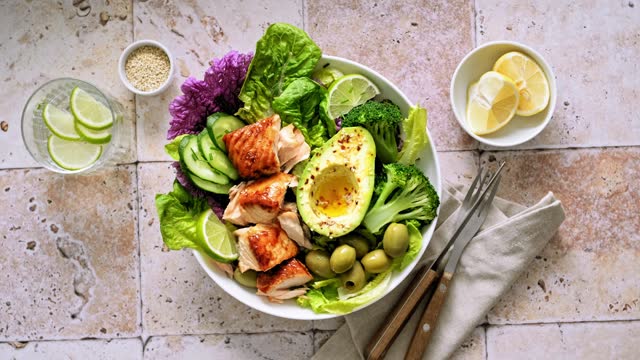 Salad bowl of salmon, avocado, broccoli, olives and fresh Romaine lettuce. Poke bowl salad, stock footage video 4K