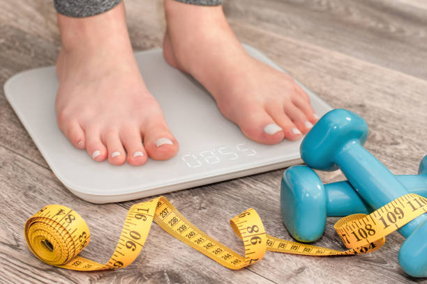 los pies descalzos femeninos se paran sobre escamas - báscula de baño fotografías e imágenes de stock
