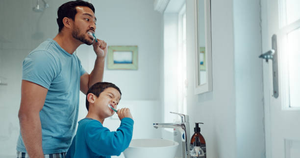 istock Father, child and brushing teeth in family home bathroom while learning or teaching dental hygiene. A man and kid with toothbrush and toothpaste for health, cleaning mouth and wellness at mirror 2029952957