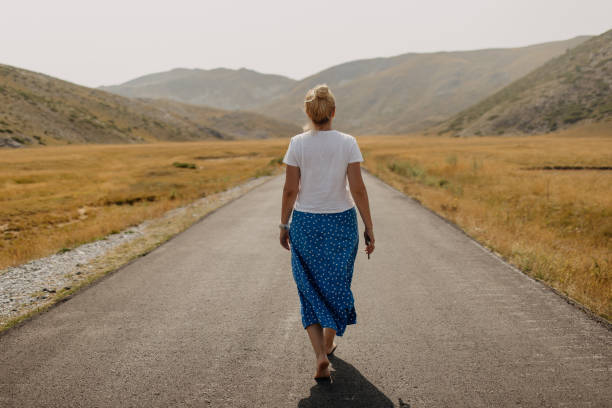 One woman walking on empty road
