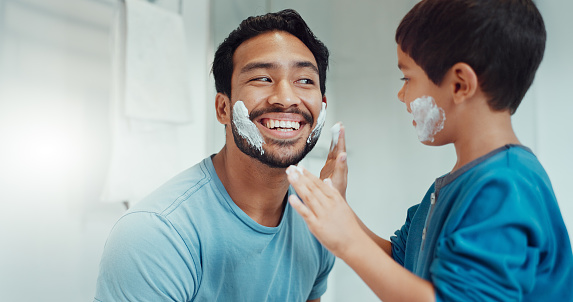Shaving, bathroom and father teaching child about grooming, playing hygiene and facial routine. Playful, help and dad showing boy kid cream or soap for hair removal together in a house in the morning
