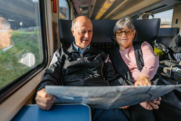 Senior Couple Reading A Map While Riding In A Train In Switzerland