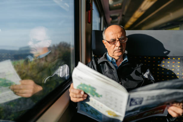 Senior man reading a newspaper while riding in a train in Switzerland.