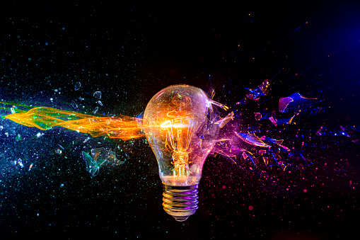 Vivid image of a light bulb shattering with a dynamic multicolored glass fragment splash