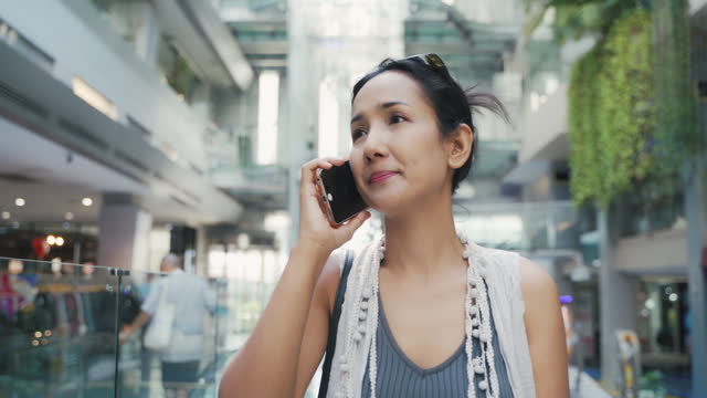 Business woman using smartphone while walking and talking in department store.