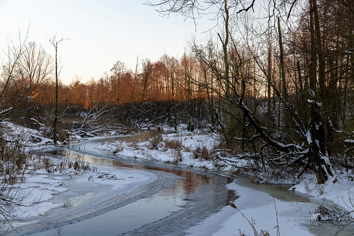ice-covered water in a river in winter, sunset on a river whose banks are covered with ice
