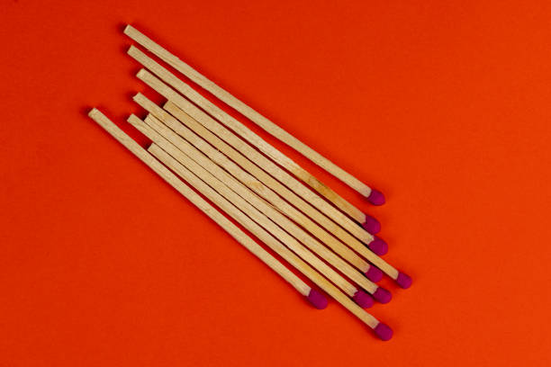 long wooden matches on a paper background, matches with a red pink substance for lighting on an orange background
