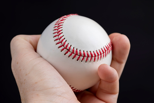 white baseball ball tied with red thread, a real round baseball ball close-up