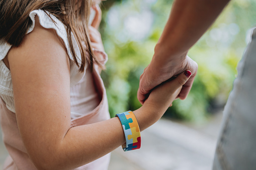 Autistic child holding hands with his mother