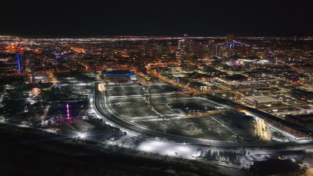 Denver downtown i25 highway traffic aerial drone snowy winter evening dark night city lights landscape Colorado cinematic anamorphic Elitch Gardens Ball Arena circle left movement