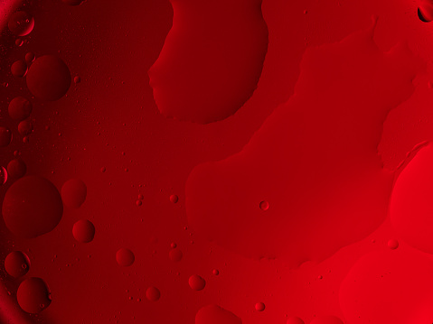 Vivid red bubbles of various sizes create an abstract, fluid texture.