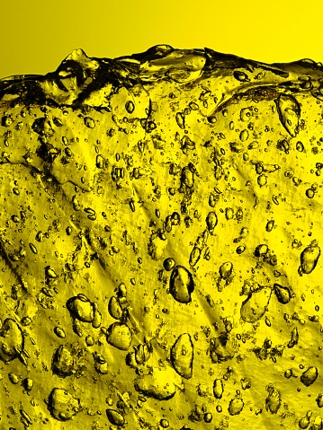 Close-up of a vibrant yellow ice texture featuring trapped air bubbles.