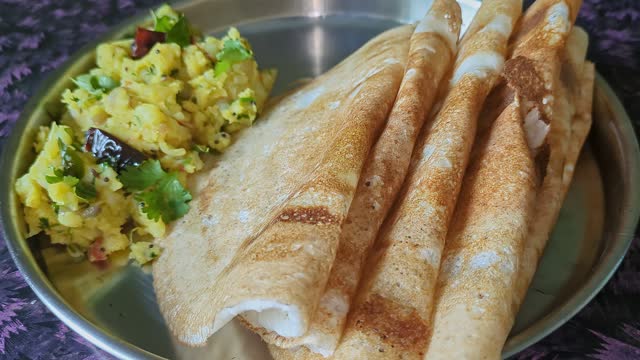 Closeup video of homemade crispy dosa with mashed potatoes served on a silver plate