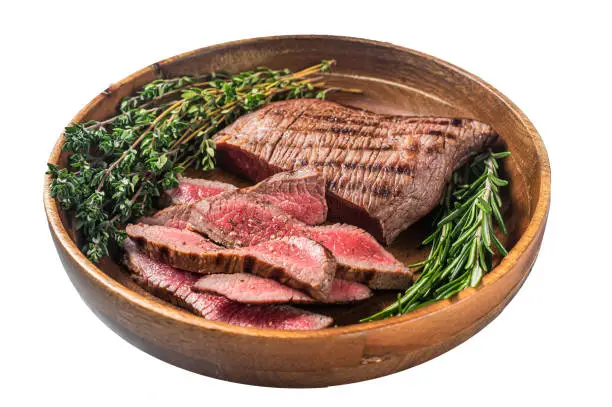 Photo of Grilled sliced Skirt Steak on a plate with herbs.  Isolated on white background.