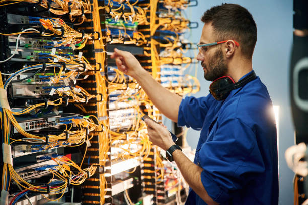 istock Holding smartphone. Young man is working with internet equipment and wires in server room 2030098002