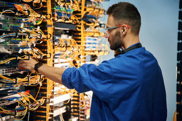 istock Restoring the internet connection. Young man is working with equipment and wires in server room 2030098525