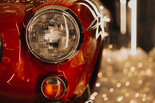 The fiery glow of a classic car's red headlight illuminates the stillness of a parked vehicle, showcasing its automotive lighting and adding a touch of nostalgia to the scene , Tbilisi , Georgia