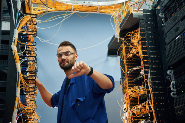 istock Showing thumb down. Young man is working with internet equipment and wires in server room 2030108191