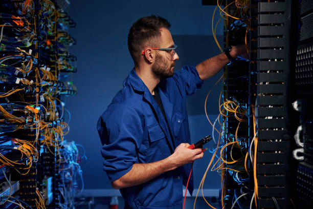 istock Blue colored lighting. Young man is working with internet equipment and wires in server room 2030110870