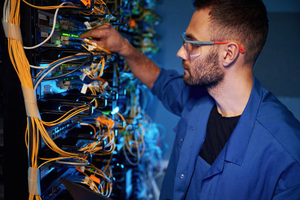 istock In glasses. Young man is working with internet equipment and wires in server room 2030113016