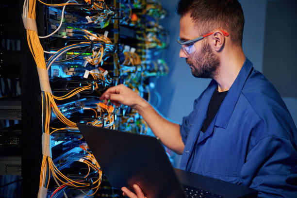 istock Cables management. Young man is working with internet equipment and wires in server room 2030113023