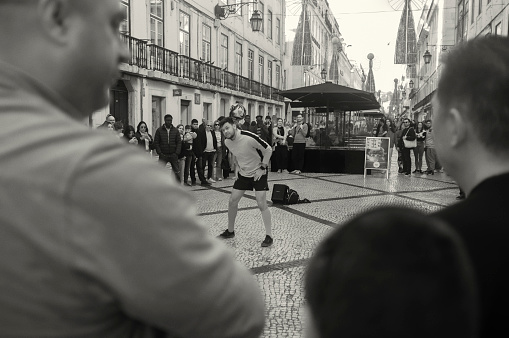 Lisbon, Portugal - January 11, 2023: A street artist performs a juggling act with a soccer ball at the Rua Augusta street in Lisbon downtown.