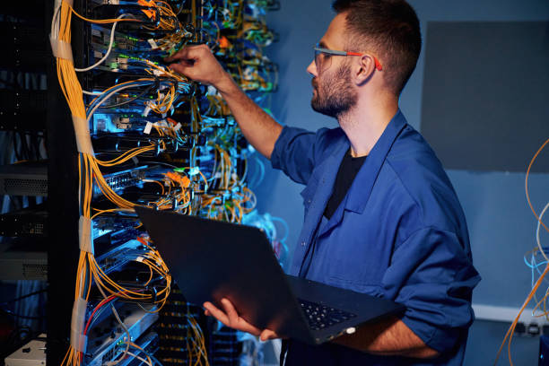 istock Cables management. Young man is working with internet equipment and wires in server room 2030113556