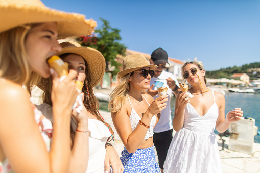 Group of gorgeous young women and man have a fun at summer in the beautiful village Fiscardo on Kefalonia island in Greece. Beautiful young people are friends. They traveling together and looks very happy